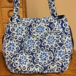 A blue and white floral patterned handbag sits on a wooden surface.