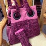 A pink and purple patterned tote bag with a matching pouch on a chair.