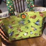 A colorful tote bag with cartoon character prints sits on a wooden chair.