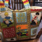Colorful quilted bag with illustrations of children reading, numbers, alphabet, and measuring tape handles on a wooden chair.