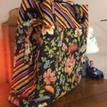 Colorful floral and striped fabric tote bag on a wooden surface next to a small figurine.