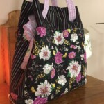 A floral-patterned bag with purple handles placed on a wooden surface.