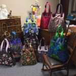 A collection of colorful patterned tote bags displayed on rocking chairs and a dresser in a room.