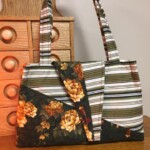 Patchwork handbag with floral and striped patterns, placed on a wooden surface near a wooden drawer unit.