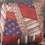 Patchwork cushion featuring red, purple, and patterned fabric pieces on a gray chair.