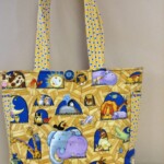 Colorful fabric tote bag with animal print, featuring elephants, giraffes, and lions on a wooden texture background.