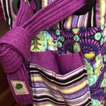 A colorful, patterned bag with purple straps and a mix of stripes and floral designs in green, blue, and yellow tones.