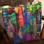 Colorful quilted bag featuring a vibrant cityscape design sits on a wooden chair.