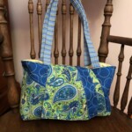 Colorful handmade tote bag with paisley and striped patterns on a wooden chair.