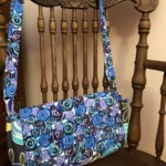 A colorful shoulder bag with spiral patterns hangs on a wooden chair with a carved backrest.