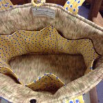 Open yellow and blue polka dot bag with multiple interior pockets, featuring a "Creative Craftworks" label inside.