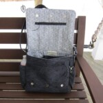 Black quilted handbag with a patterned interior and multiple pockets, placed open on a wooden bench.