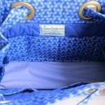 The interior of a blue fabric bag with eyelets, featuring a Creative Craftworks label and a floral pattern.