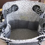 Open black and white polka dot bag with multiple interior pockets and gray lining.
