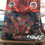 A fabric tote bag with a floral pattern and metal grommets on a wooden chair.