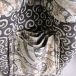 Fabric bag with intricate floral and swirl patterns, showing multiple interior pockets folded inside.