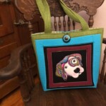 Colorful tote bag with a dog design on the front, hanging on a wooden chair.