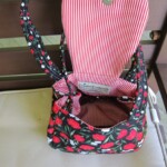 An open floral-patterned handbag with a red and white striped interior on a bench.