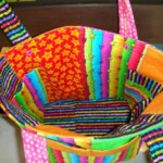 Colorful quilted bag with bright, multicolored patterns including stars and stripes, shown with an open view of the interior.