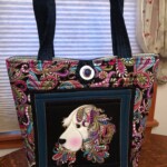 Colorful tote bag with patterned handles and a button closure, featuring a detailed dog design on the front pocket.