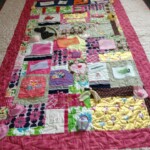 A colorful patchwork quilt with various patterns, floral designs, and text on a light background.