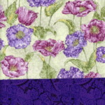 Patterned fabric with purple and pink flowers on a green background, and a dark purple paisley band at the bottom.