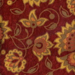 A rich red fabric with a floral pattern featuring gold, brown, and orange flowers and leaves in a decorative design.