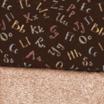 Patterned fabric with colorful alphabet letters on a dark background, above a textured beige fabric.