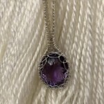 Purple gemstone pendant surrounded by silver wire wrapping on white background at Creative Craftworks