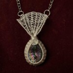 Wire-wrapped pendant featuring an iridescent teardrop gemstone and circular opalescent stone on a silver chain