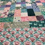 A colorful patchwork quilt with various floral and geometric patterns covering a large surface.